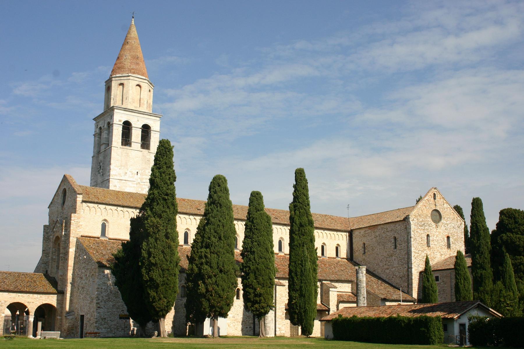 Romanesque Basilica of Aquileia and its bell tower framed by tall cypresses