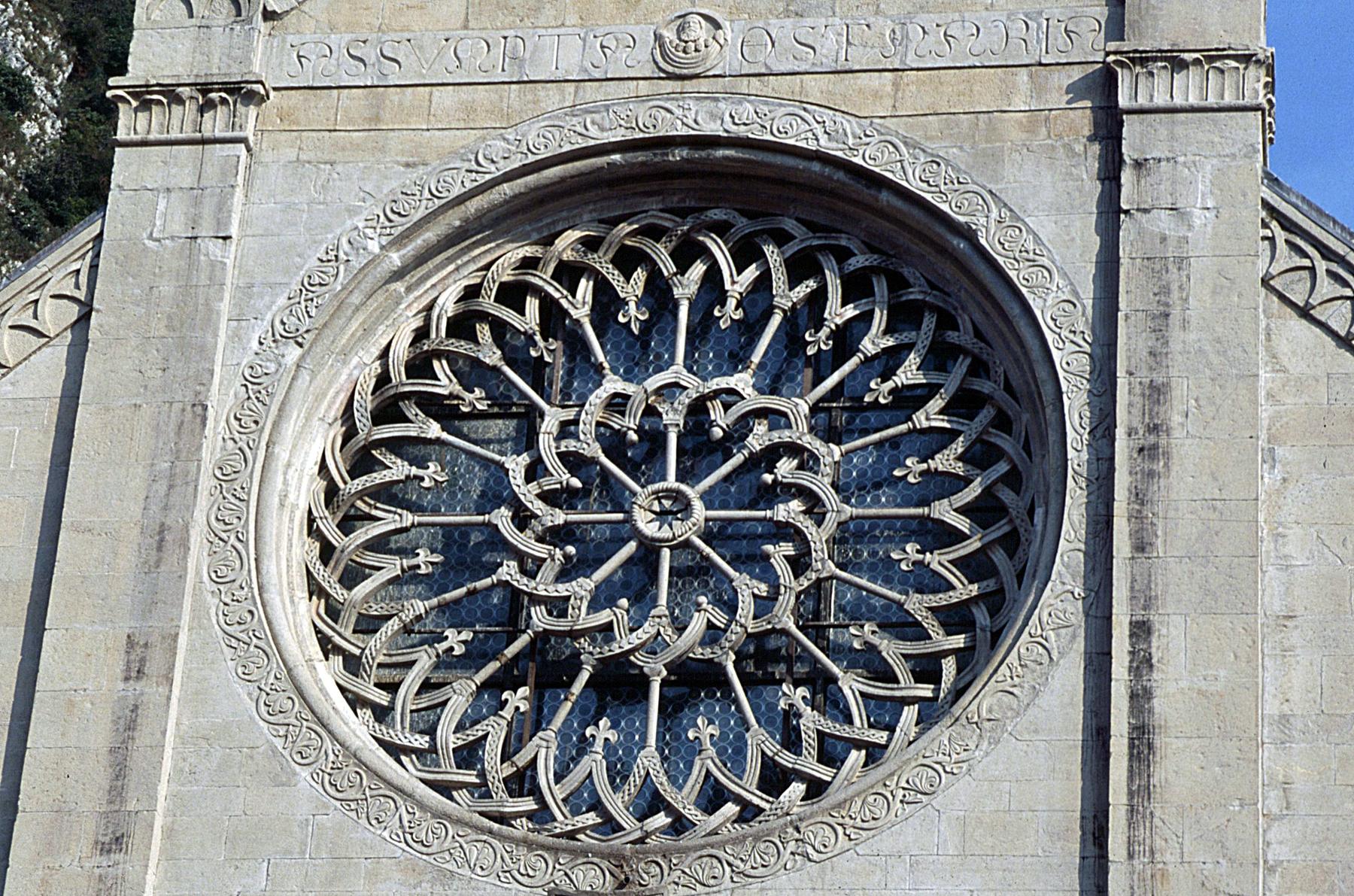 Intricate Gothic rose window carved in pale stone on Gemona cathedral