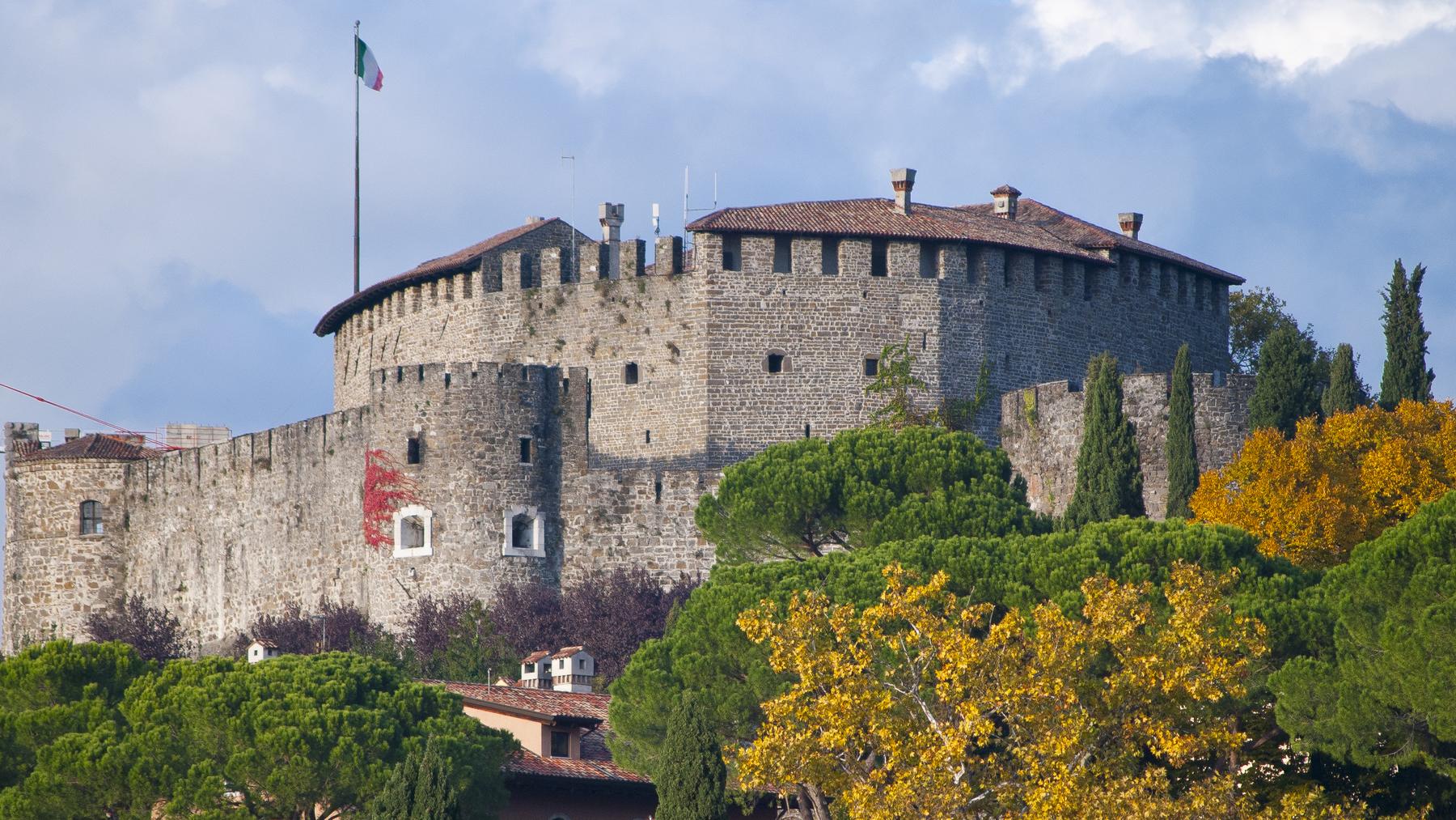 Gorizia Castle's medieval walls rising above autumn trees