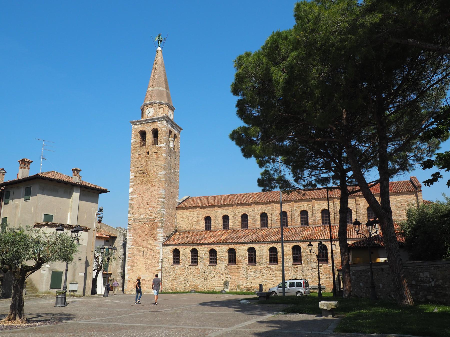 Basilica of Sant'Eufemia and its bell tower under a blue sky in Grado