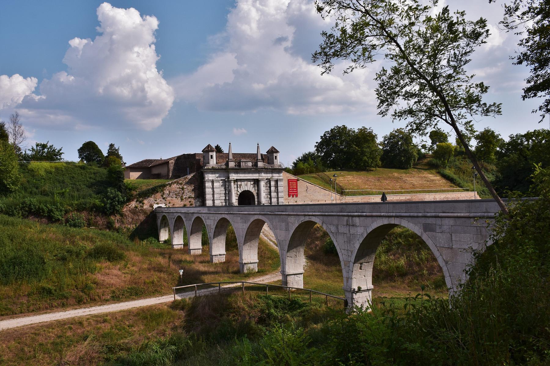 Arched stone bridge across the moat to Porta Udine in Palmanova's ramparts