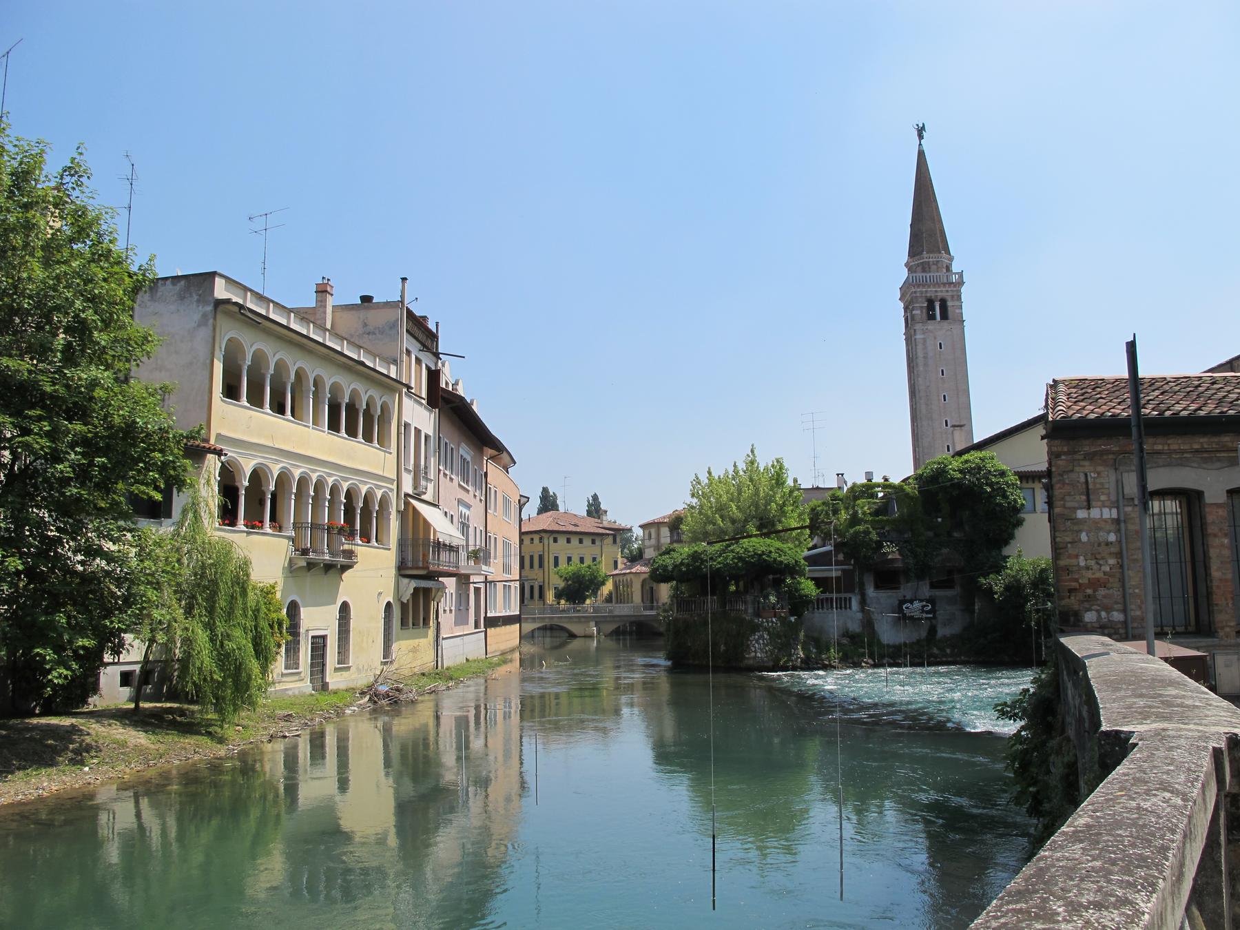 The Livenza river flowing past palaces and the cathedral bell tower in Sacile