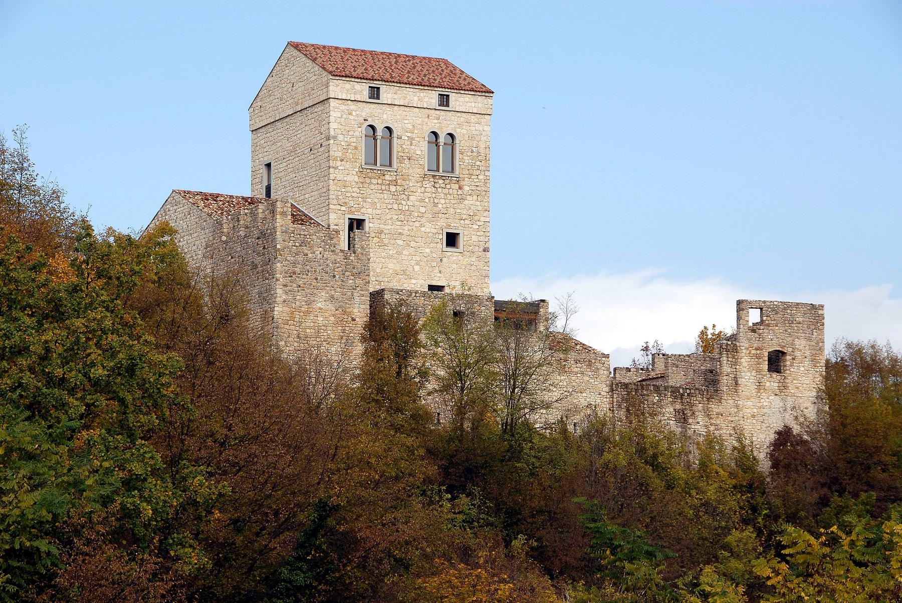 Medieval stone keep and walls of Castello di Ragogna amid autumn woods