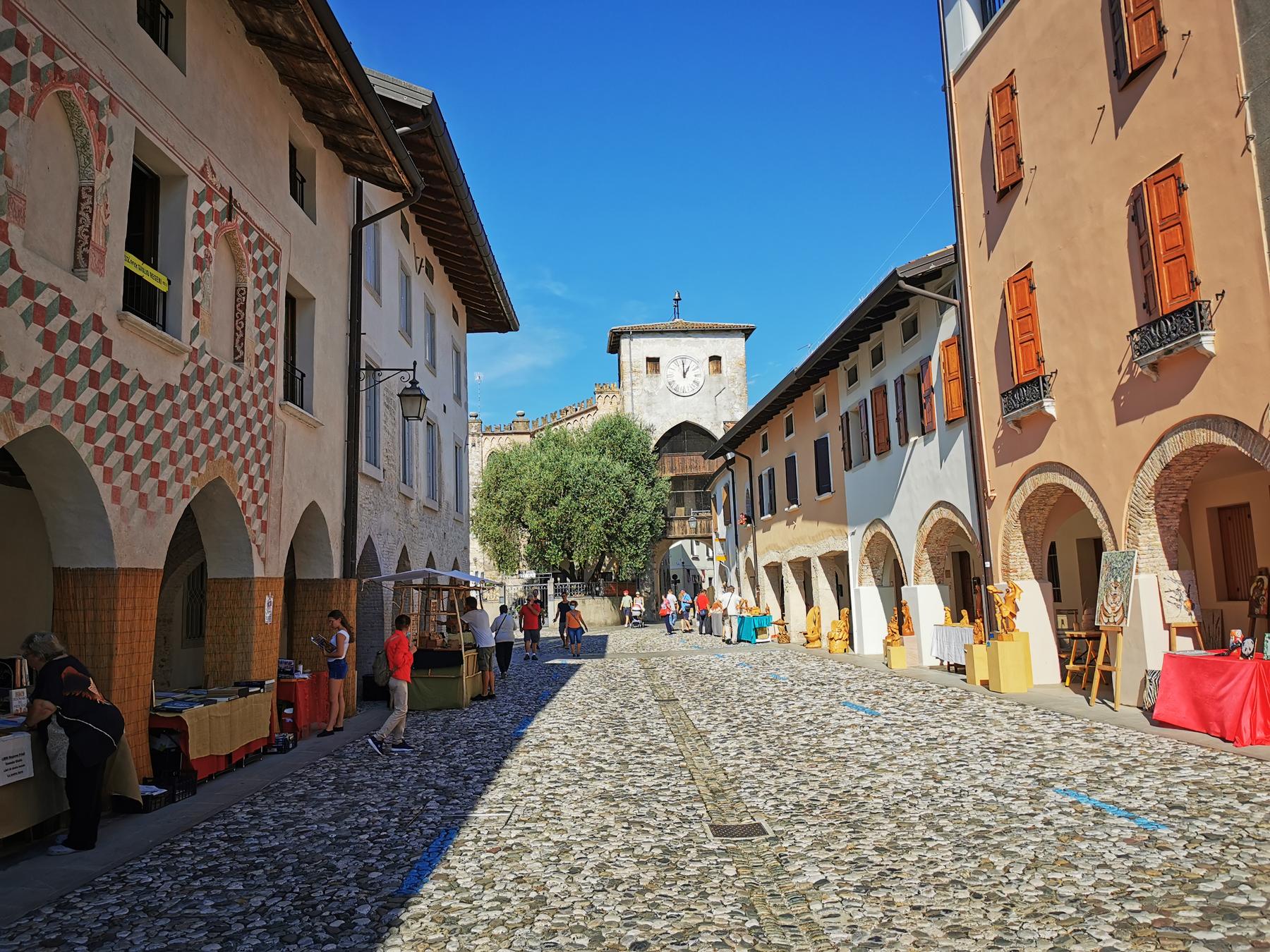 Cobbled Corso Roma in Spilimbergo with arcades, painted houses and clock tower