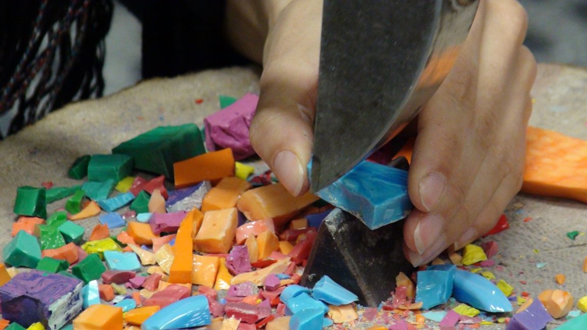 Cutting colourful glass tesserae with a hammer at the Mosaic School in Spilimbergo