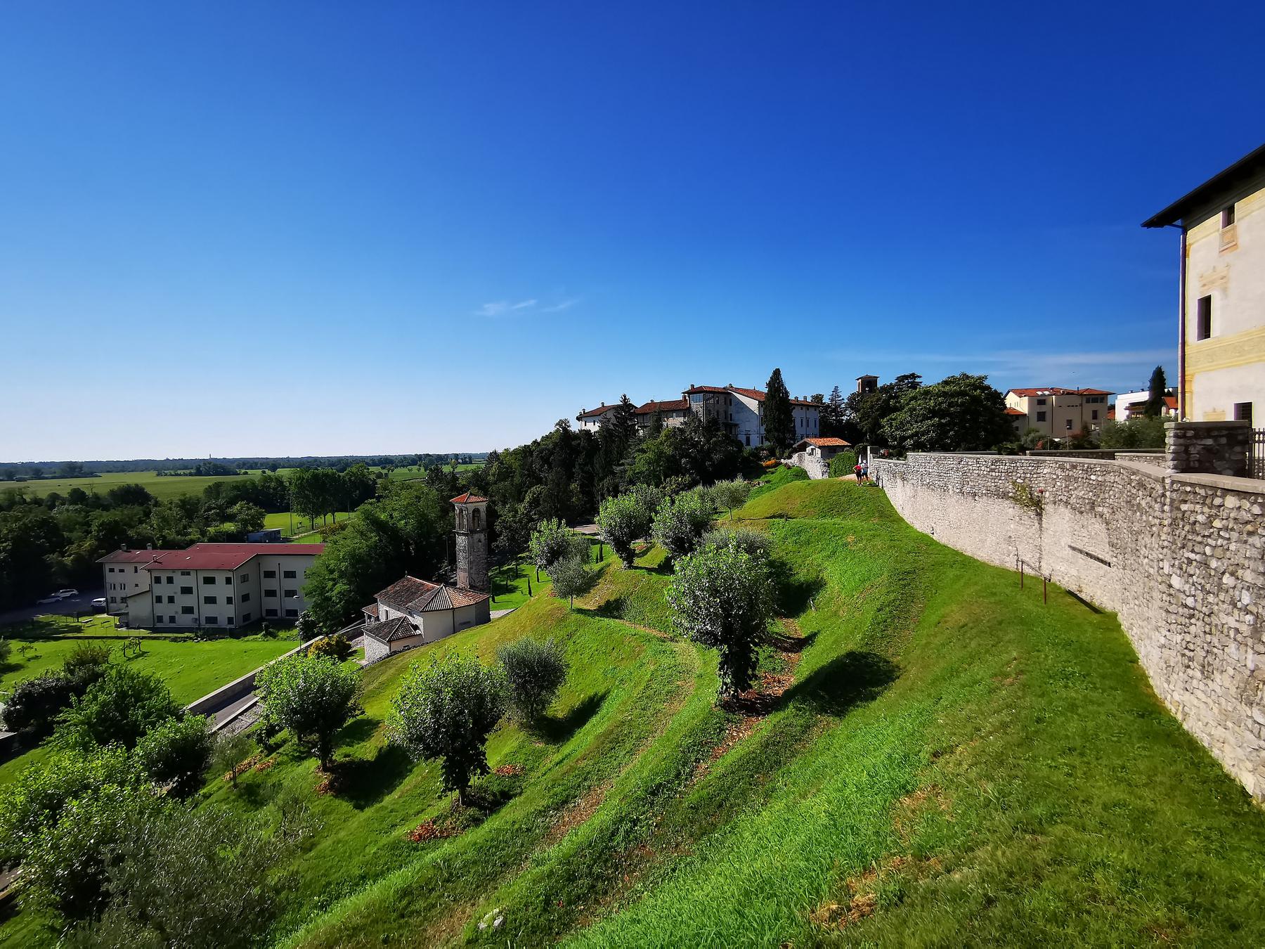 Green slopes and old walls below Spilimbergo's castle hill looking over the plain